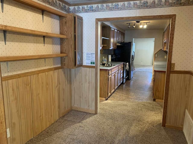 kitchen with light colored carpet, a wainscoted wall, a sink, open shelves, and wallpapered walls