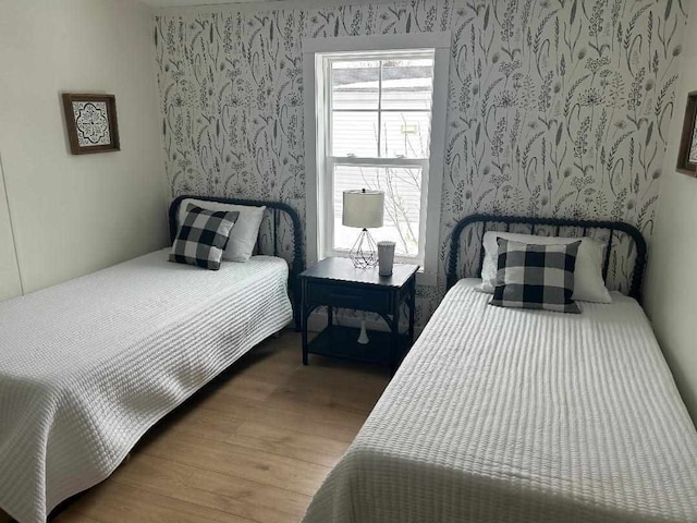 bedroom featuring wood finished floors and wallpapered walls