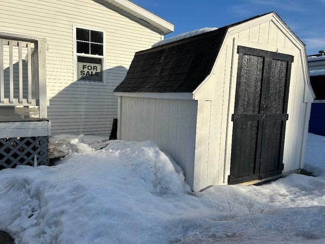 snow covered structure with an outdoor structure and a storage shed