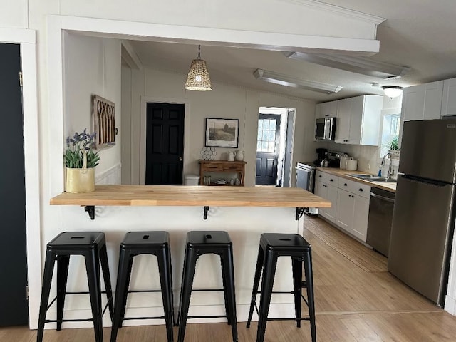 kitchen with light wood finished floors, a breakfast bar area, stainless steel appliances, and a sink