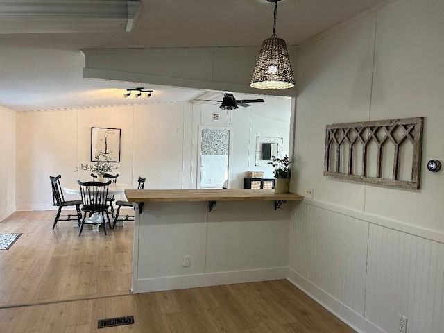 kitchen featuring light wood finished floors, lofted ceiling, visible vents, hanging light fixtures, and a ceiling fan