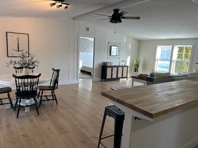 dining room featuring light wood-style floors, visible vents, ceiling fan, and lofted ceiling with beams