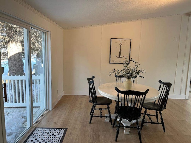 dining space with ornamental molding, baseboards, and light wood finished floors