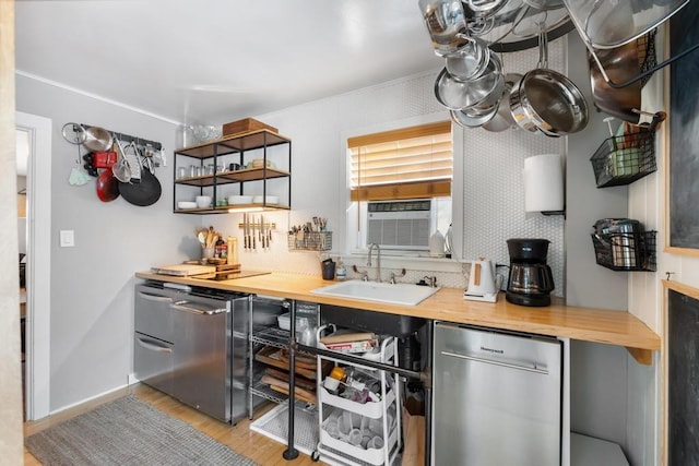 kitchen featuring butcher block countertops, light wood-type flooring, a sink, and stainless steel dishwasher