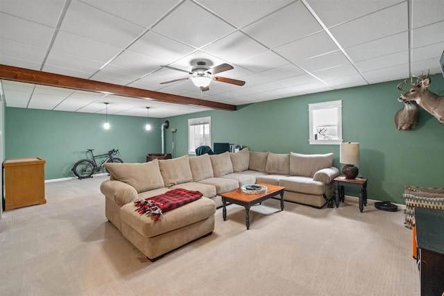 living area with ceiling fan, baseboards, a drop ceiling, and carpet flooring