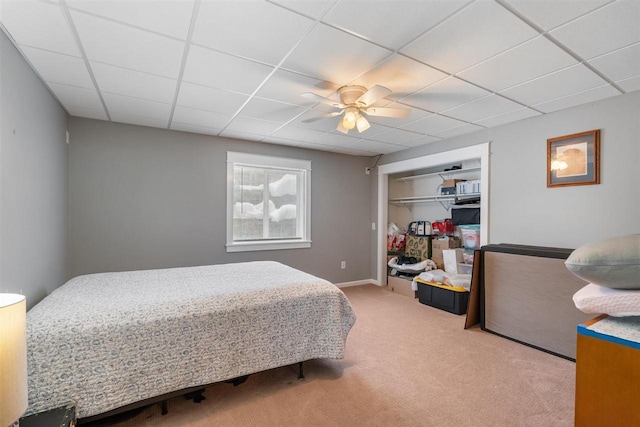 bedroom featuring a paneled ceiling, carpet floors, a ceiling fan, baseboards, and a closet