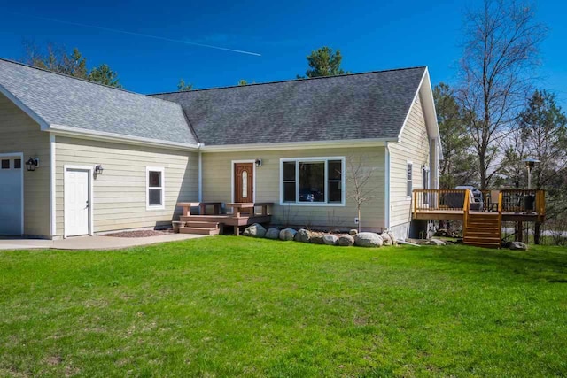 back of house featuring a shingled roof, a yard, a deck, and an attached garage