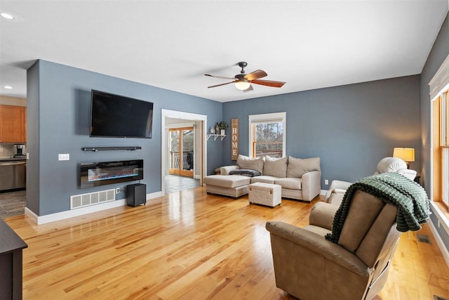 living room featuring wood finished floors, visible vents, and baseboards