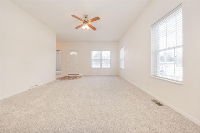 unfurnished room with a ceiling fan, visible vents, light carpet, and baseboards