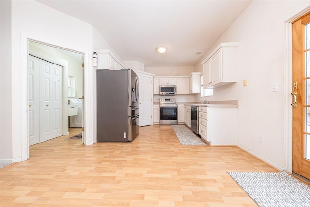 kitchen with light wood finished floors, baseboards, washer / clothes dryer, stainless steel appliances, and white cabinetry