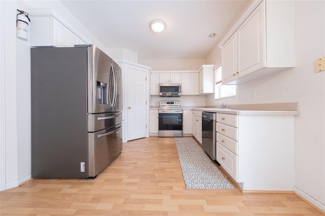 kitchen featuring appliances with stainless steel finishes, light wood-type flooring, and white cabinetry