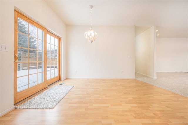 empty room with baseboards, light wood finished floors, visible vents, and an inviting chandelier