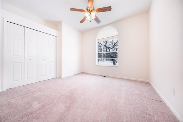 unfurnished bedroom featuring a closet, carpet, a ceiling fan, and baseboards