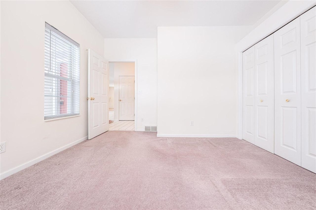 unfurnished bedroom with a closet, carpet flooring, visible vents, and baseboards