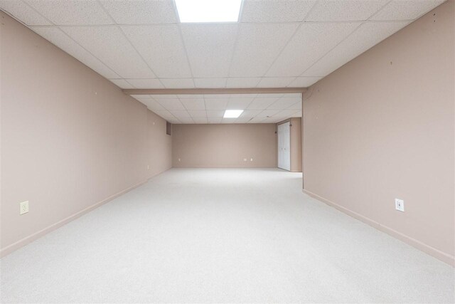 finished basement with carpet floors, a paneled ceiling, and baseboards