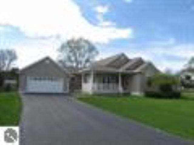 view of front of property with an attached garage, aphalt driveway, and a front lawn