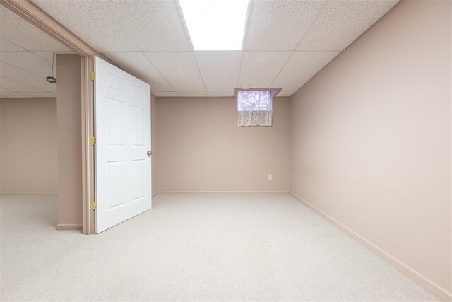 basement featuring carpet floors, a paneled ceiling, and baseboards