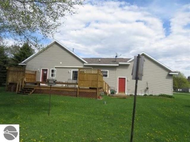 rear view of property featuring a lawn and a deck