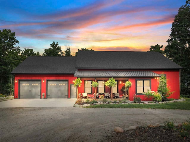 view of front of home featuring driveway, metal roof, an attached garage, a standing seam roof, and a porch