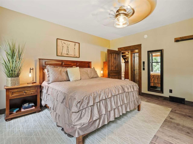 bedroom with a ceiling fan, light wood-style flooring, visible vents, and baseboards