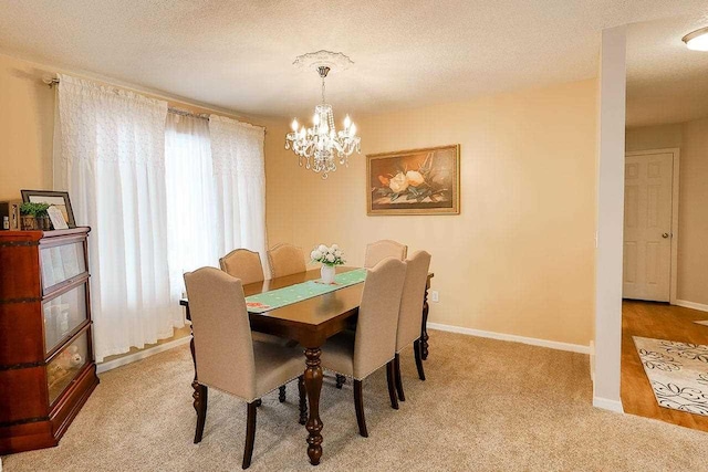 dining space with a textured ceiling, a chandelier, and baseboards