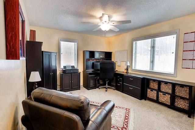 office featuring light carpet, ceiling fan, and a textured ceiling