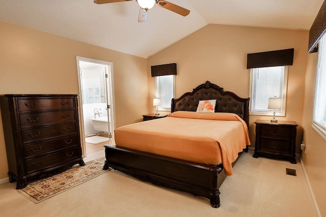 bedroom with light colored carpet, visible vents, ensuite bathroom, a ceiling fan, and vaulted ceiling