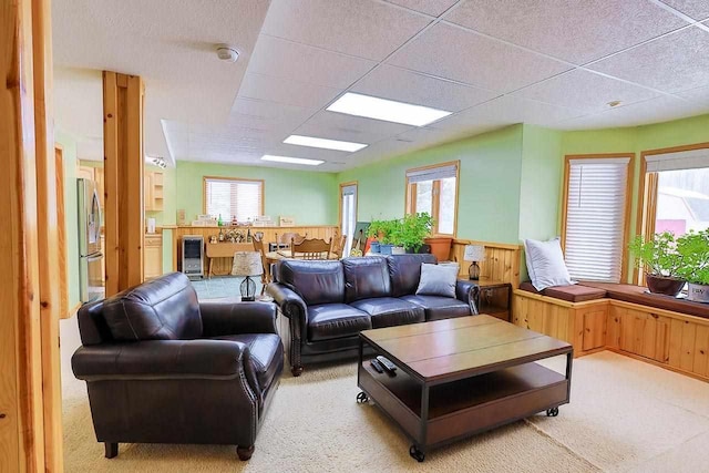 living room with beverage cooler, light colored carpet, and a drop ceiling