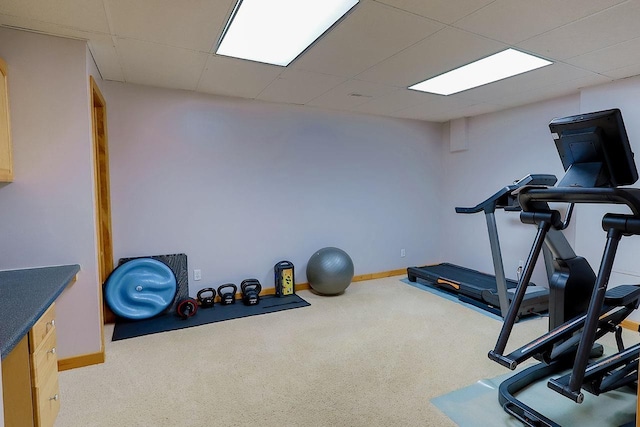 exercise area featuring carpet, a drop ceiling, and baseboards