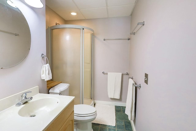 full bath with a drop ceiling, toilet, vanity, baseboards, and a shower with door