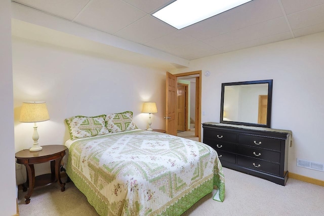 carpeted bedroom featuring a paneled ceiling, visible vents, and baseboards