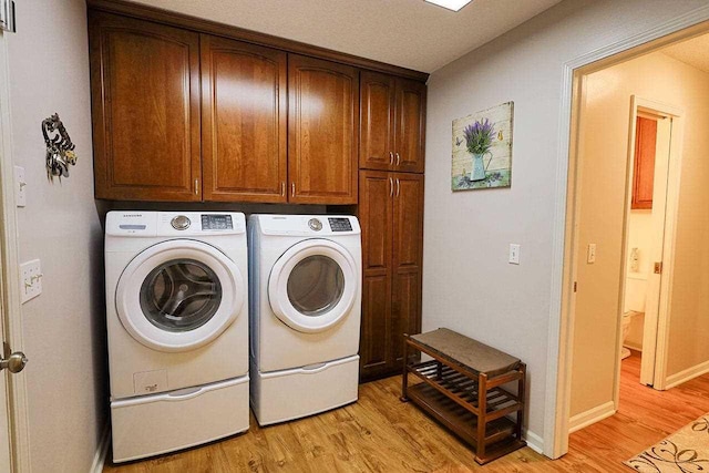 laundry room featuring baseboards, light wood-style flooring, cabinet space, and washer and dryer