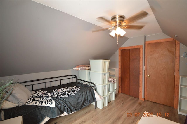 bedroom featuring lofted ceiling, wood finished floors, a ceiling fan, and multiple closets