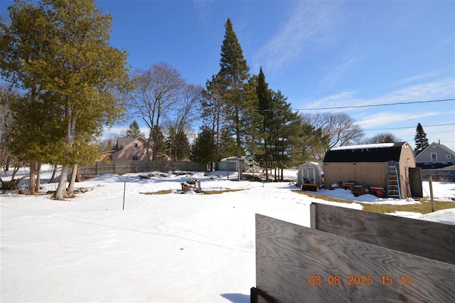 yard covered in snow featuring an outdoor structure, fence, and a storage unit