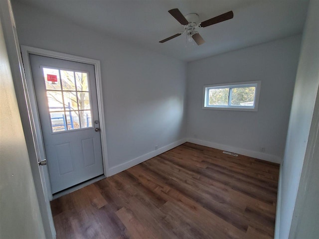 doorway featuring a ceiling fan, visible vents, baseboards, and wood finished floors