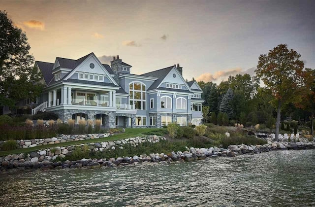 rear view of property with a water view and stone siding