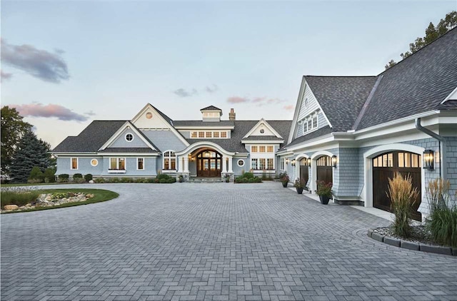 shingle-style home with a garage and decorative driveway