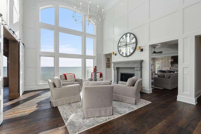 living area with dark wood-type flooring, a notable chandelier, a decorative wall, and a fireplace