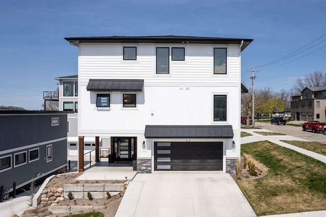 view of front of house with a standing seam roof, stone siding, a garage, and driveway