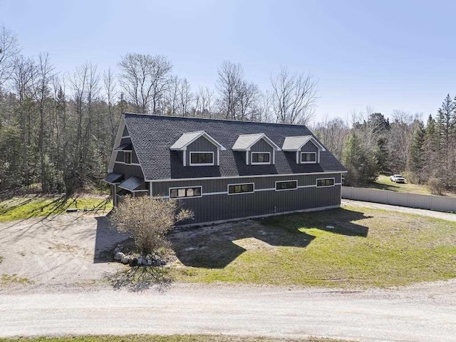 view of front of property featuring roof with shingles, a front yard, and fence