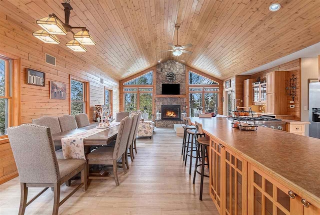 dining space with high vaulted ceiling, wooden walls, light wood finished floors, wood ceiling, and ceiling fan