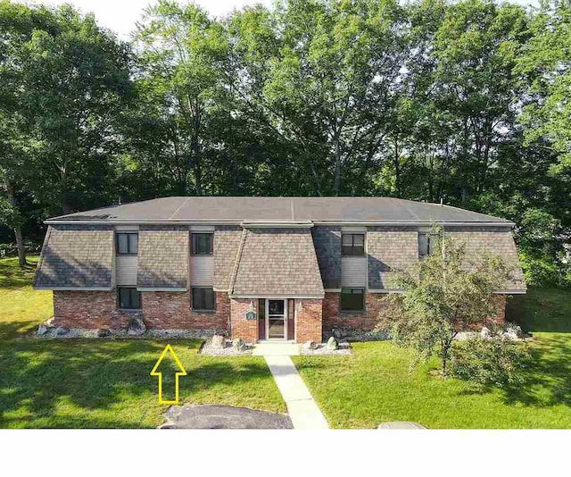 view of front facade with brick siding and a front lawn