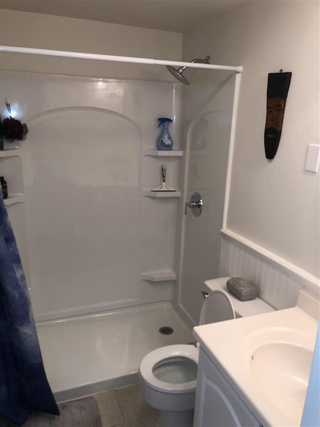 bathroom featuring vanity, a stall shower, wainscoting, tile patterned floors, and toilet