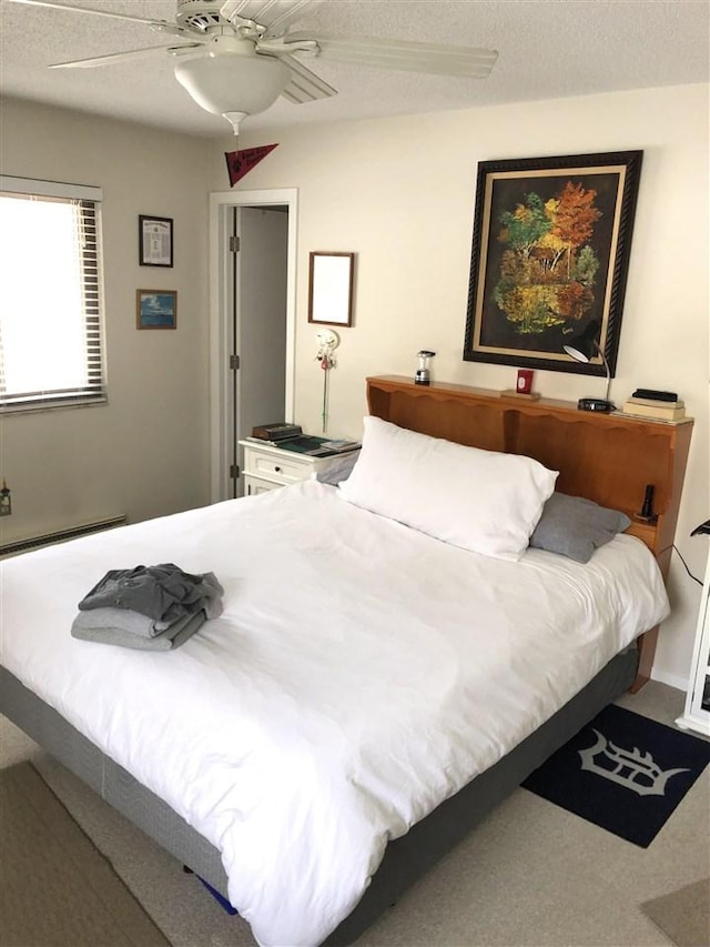 carpeted bedroom with a textured ceiling, a ceiling fan, and a baseboard radiator