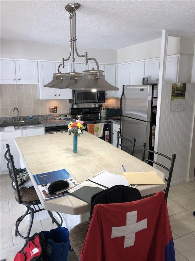 kitchen featuring a sink, decorative backsplash, tile counters, appliances with stainless steel finishes, and white cabinetry