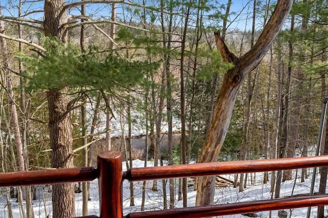 snow covered deck featuring a wooded view