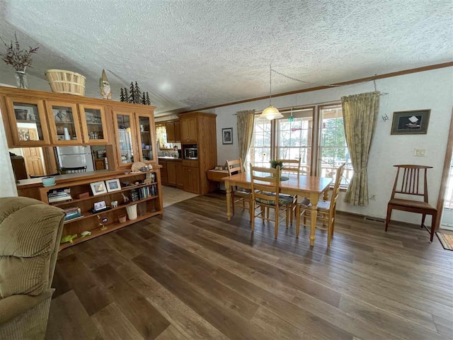 dining area featuring crown molding, dark wood-style floors, and a textured ceiling