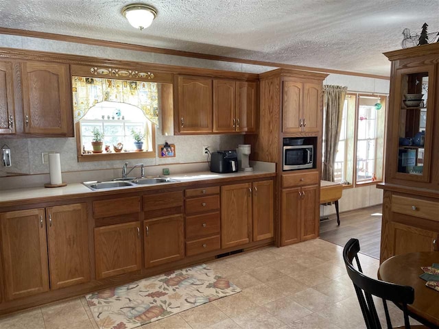 kitchen featuring brown cabinetry, light countertops, and a sink