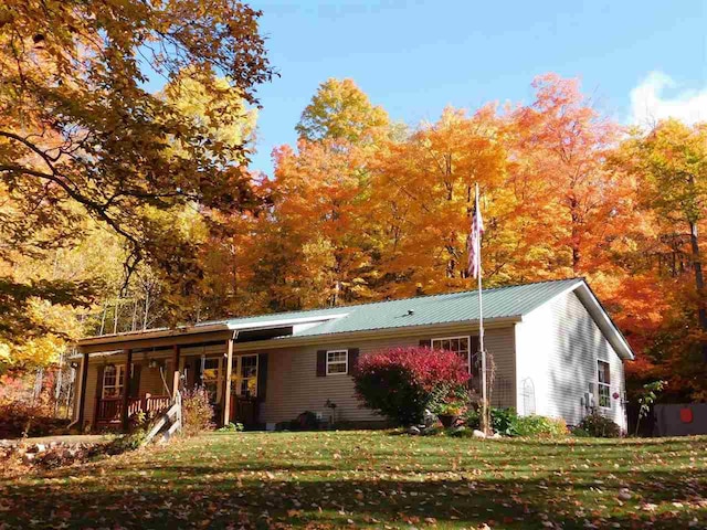 single story home featuring metal roof, a porch, and a front yard