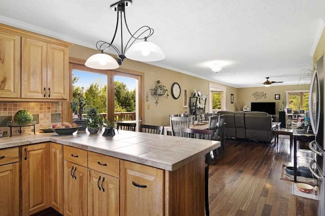 kitchen featuring ornamental molding, tasteful backsplash, tile countertops, a peninsula, and dark wood-style flooring